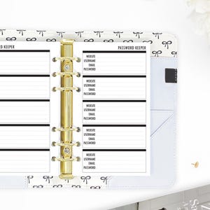 May include: A white password keeper with a gold binder and black text. The text reads "PASSWORD KEEPER" and includes sections for website, username, email, and password.