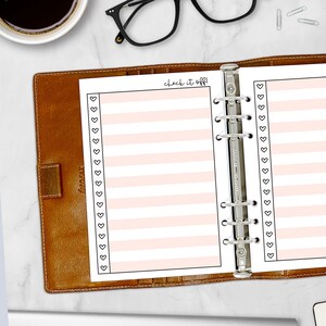 Printed A5 Check It Off checklist planner insert in Peach shown in a tan leather ring binder on a marble desk. Peach striped design with heart checkboxes. Physical paper insert only -- binder and accessories not included. Planner insert is made in the USA by CityGirl Planners.