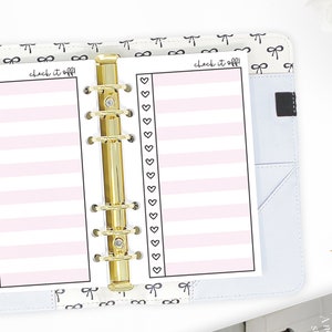 May include: A white planner page with pink stripes and a black border. The page has the text "check it off!" written at the top and a column of hearts down the left side. The page is in a gold binder.