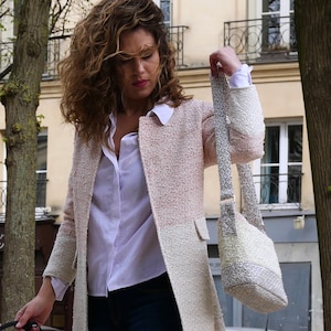 Peut inclure: Une femme portant une chemise blanche et une veste en tweed rose et blanche avec un sac à bandoulière blanc et gris.