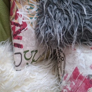 Puede incluir: Tres almohadas decorativas con diferentes patrones. Una almohada es blanca con una textura esponjosa, otra es gris con una textura esponjosa y la tercera es blanca con un dise&ntilde;o de estilo graffiti colorido.