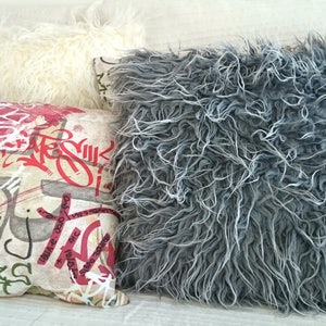 Puede incluir: Cuatro almohadas decorativas con diferentes texturas y patrones. Una almohada es blanca y esponjosa, otra es gris y esponjosa, una es roja y la &uacute;ltima es beige con letras de estilo graffiti rojo y negro.