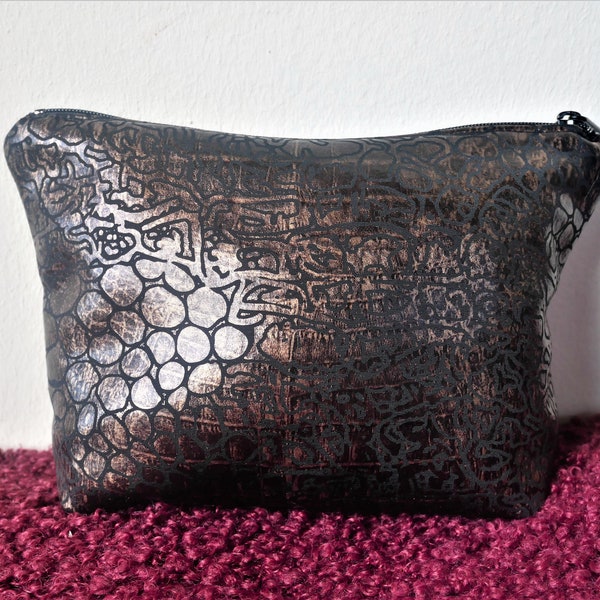 Petite pochette fermée par un zip, Trousse à maquillage en tissu noir à motif peau de serpent bronze doré.