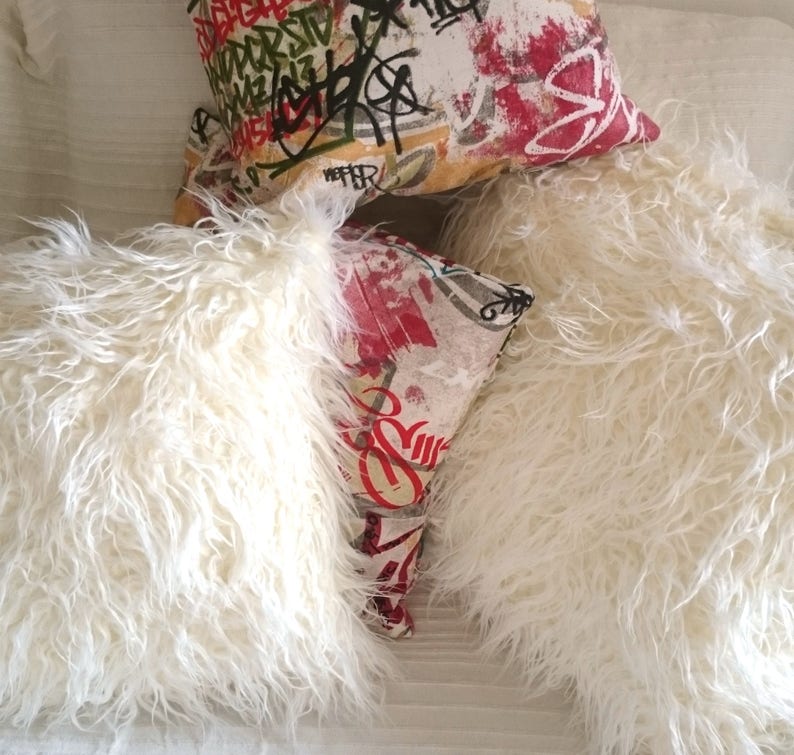 Puede incluir: Dos almohadas blancas y esponjosas con una almohada estampada de colores encima. La almohada estampada es roja, blanca y negra con dise&ntilde;os abstractos.
