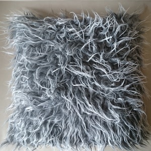 Puede incluir: Una almohada gris y blanca esponjosa con una textura suave y afelpada. La almohada est&aacute; hecha de piel sint&eacute;tica y es perfecta para agregar un toque de comodidad y estilo a cualquier habitaci&oacute;n.