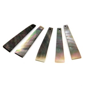 May include: Five iridescent rectangular mother-of-pearl pieces with a hole at the top. The pieces have a dark grey base color with hints of green, pink, and yellow. The pieces are arranged on a white background.