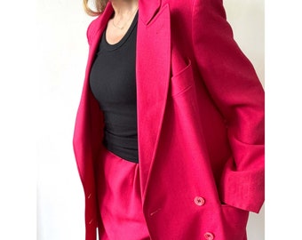 May include: A bright pink blazer and matching pants. The blazer has a double breasted closure and a pocket on the left side.