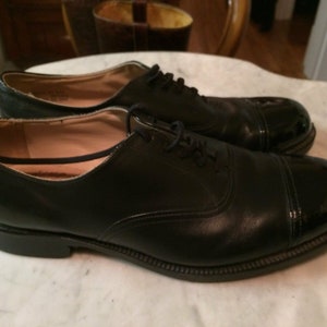 May include: A pair of black leather lace-up shoes with a patent leather cap toe.