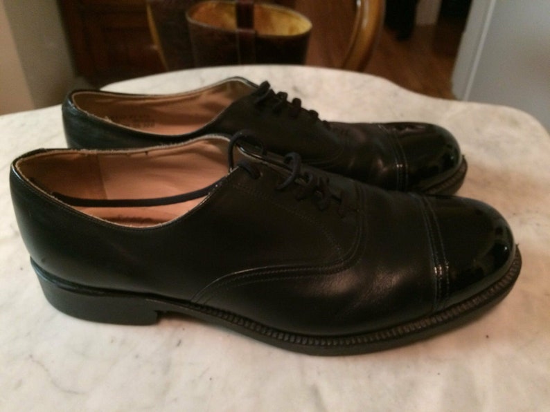 May include: A pair of black leather lace-up shoes with a patent leather cap toe.