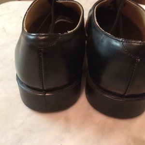 May include: A pair of black leather lace-up shoes with a rounded toe and a thick sole.