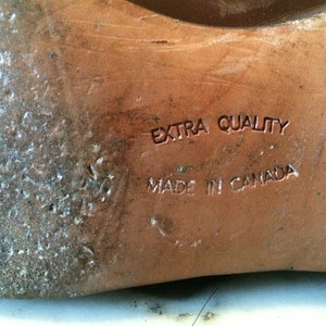 May include: Close-up of the bottom of a brown leather shoe with the text "EXTRA QUALITY MADE IN CANADA" embossed on the sole.