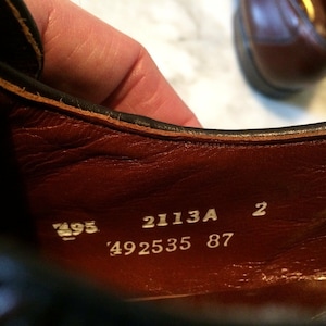 May include: Close-up of the inside of a brown leather shoe with white text that reads "2113A 2 492535 87".