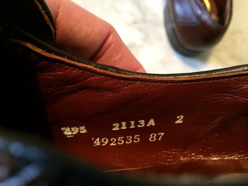 May include: Close-up of the inside of a brown leather shoe with white text that reads "2113A 2 492535 87".