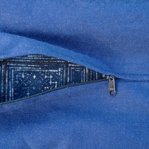 May include: A blue zippered pillow cover with a white and blue patterned fabric lining. The zipper pull is silver.