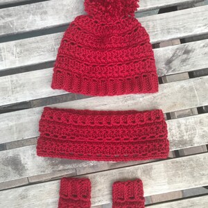 Puede incluir: Un gorro de invierno de punto rojo con un pompón, guantes sin dedos a juego y una diadema.