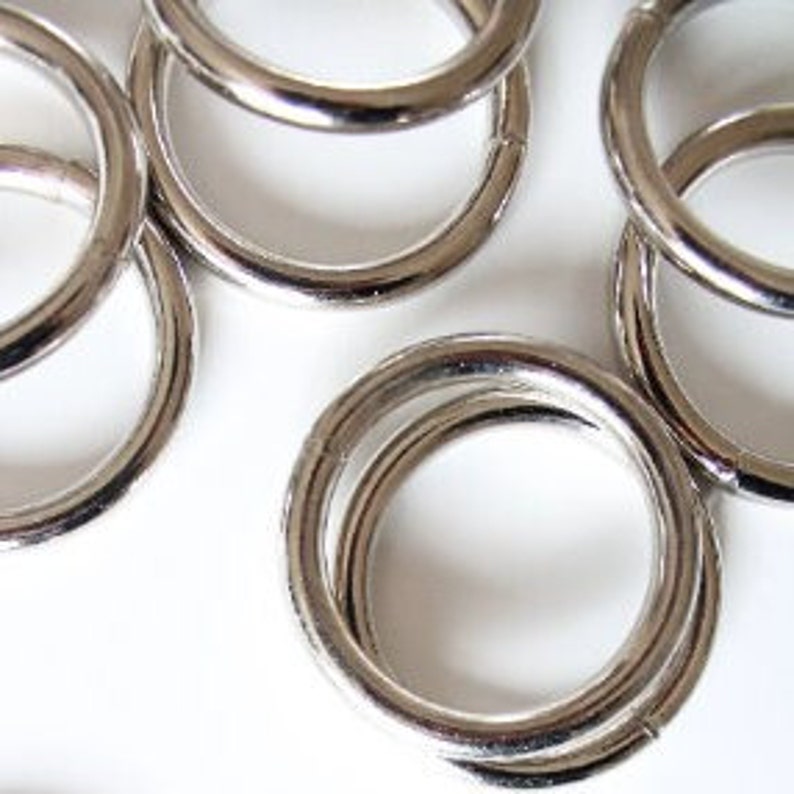 Puede incluir: Primer plano de un grupo de anillos de metal plateado. Los anillos son lisos y brillantes, y todos son del mismo tama&ntilde;o.