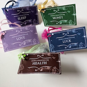 Peut inclure: Cinq petits sacs cadeaux colorés avec des étiquettes indiquant "Collection de cristaux pour le sommeil", "Collection de cristaux pour l'argent", "Collection de cristaux pour l'amour", "Collection de cristaux pour la santé" et "Collection de cristaux pour la chance".