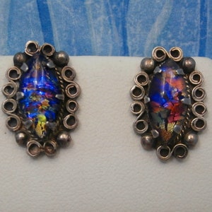 May include: A pair of silver earrings with iridescent glass stones set in a silver filigree design.