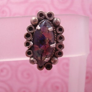 May include: A silver ring with a marbled iridescent glass stone set in a decorative silver bezel.