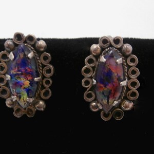 May include: A pair of silver earrings with iridescent glass stones set in a circular design.