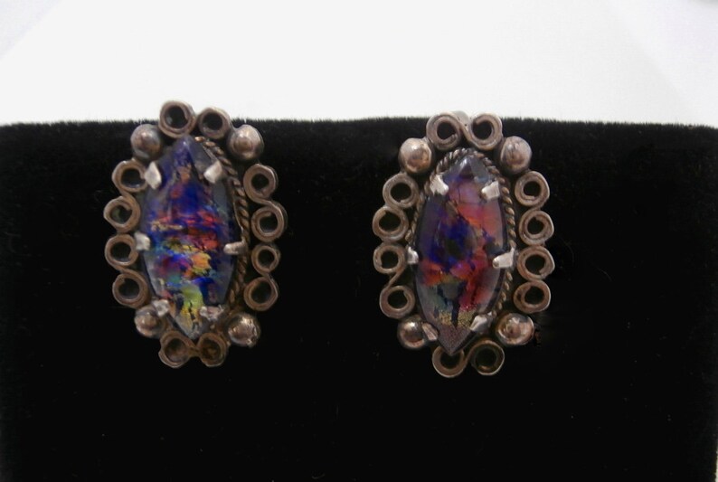 May include: A pair of silver earrings with iridescent glass stones set in a circular design.