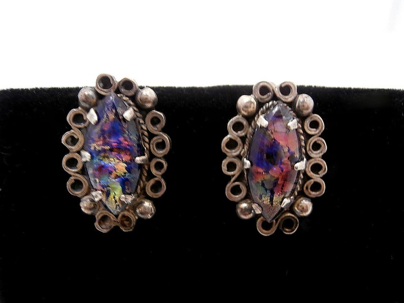 May include: A pair of silver earrings with iridescent glass stones set in a filigree design.