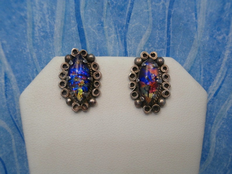 May include: A pair of silver earrings with iridescent glass stones set in a silver filigree design.