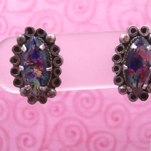 May include: A pair of silver earrings with iridescent glass stones set in a circular design.