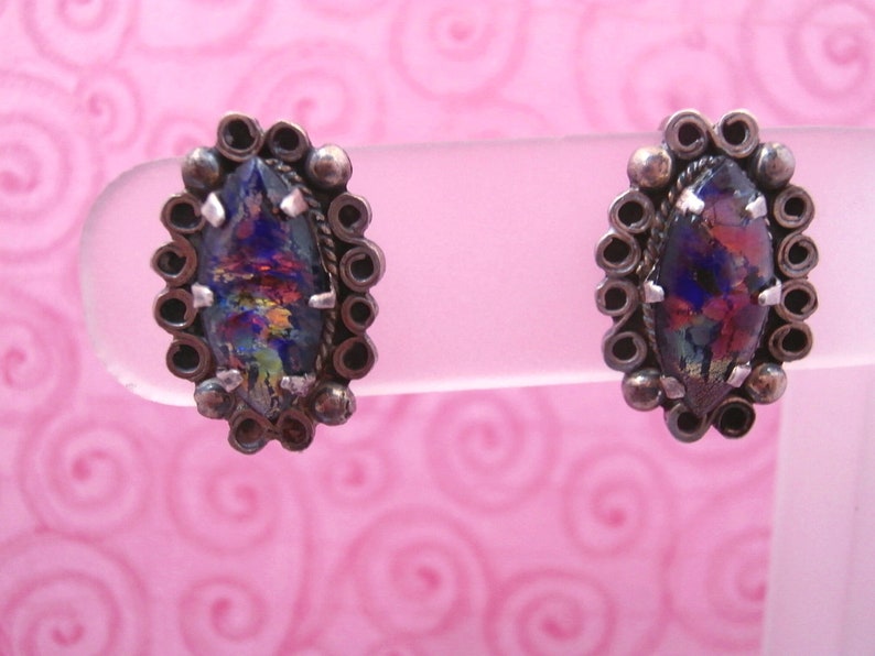 May include: A pair of silver earrings with iridescent glass stones set in a circular design.
