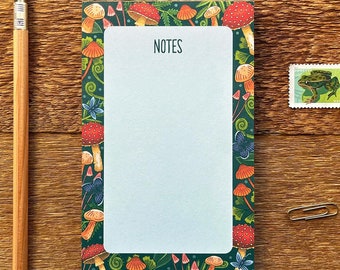 Puede incluir: Un bloc de notas con fondo verde y borde blanco. El borde está decorado con setas, hojas y enredaderas. El bloc de notas tiene la palabra "NOTES" impresa en la parte superior.