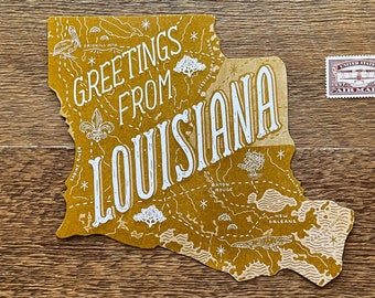 Op de afbeelding: Een gele ansichtkaart met een kaart van Louisiana. De ansichtkaart heeft de tekst "Greetings from Louisiana" in witte letters. Rechtsboven zit een klein rood-wit postzegel.