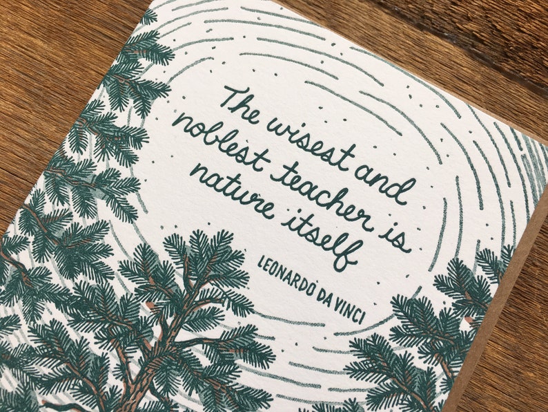 Może przedstawiać: Biała kartka z ilustracją zielonego drzewa sosnowego i cytatem "Najmądrzejszym i najszlachetniejszym nauczycielem jest sama natura" autorstwa Leonarda da Vinci.
