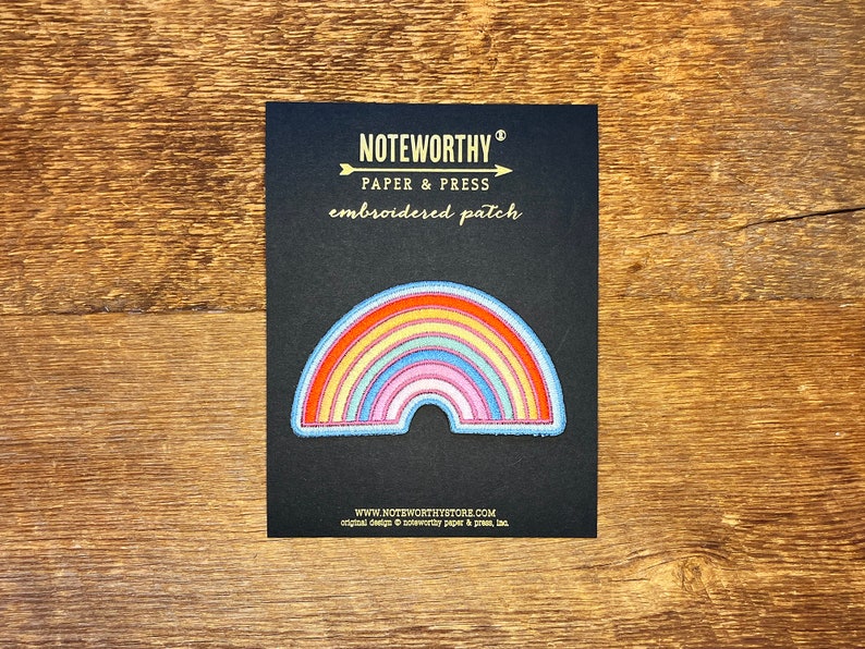 Pu&ograve; includere: Un cerotto ricamato a forma di arcobaleno su sfondo nero. Il cerotto &egrave; di Noteworthy Paper & Press e dice "embroidered patch" in lettere dorate.