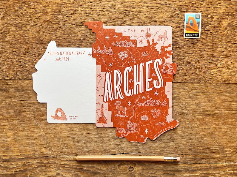 May include: A postcard featuring a map of Arches National Park in Utah. The postcard is shaped like the park and features a red and pink color scheme. The text "Arches" is written in large white letters across the map. The postcard also includes the text "Utah 1988" in the upper right corner.