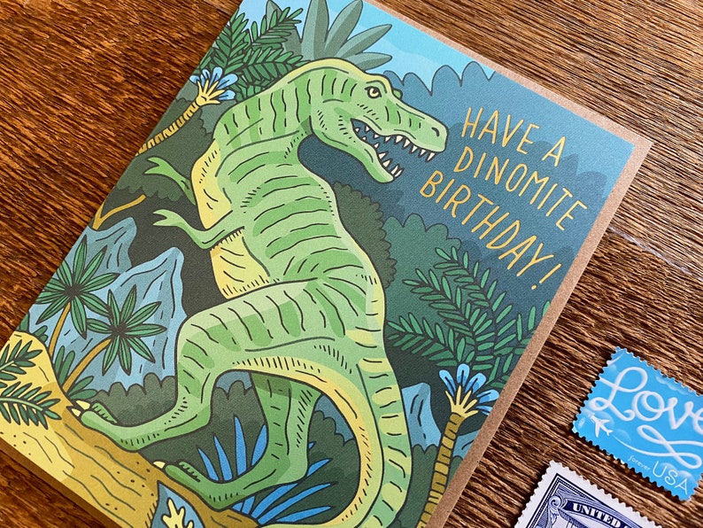 Op de afbeelding: Een groene dinosaurus met gele strepen staat in een jungle. De kaart luidt "Have a Dinomite Birthday!"