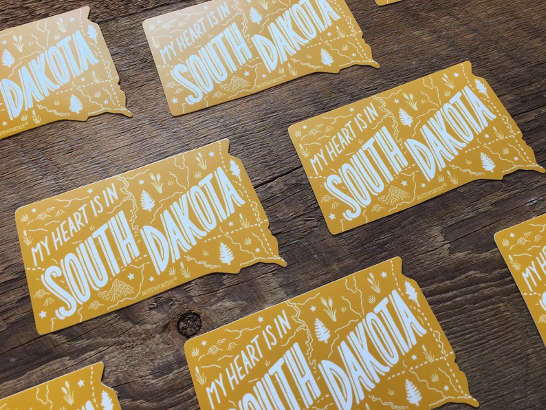 Pu&ograve; includere: Pi&ugrave; adesivi gialli con il contorno dello stato del Dakota del Sud e il testo "My heart is in South Dakota".