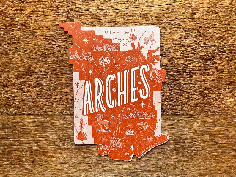 May include: A red and white illustrated map of Arches National Park in Utah. The map features a variety of landmarks, including the Delicate Arch, Balanced Rock, and the Colorado River. The word "Arches" is written in large, white letters across the map.