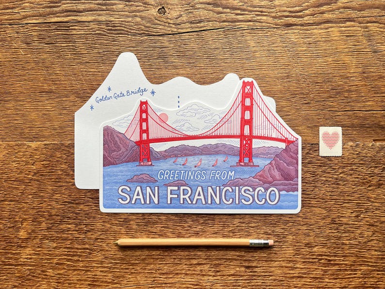 May include: A postcard featuring a red and white illustration of the Golden Gate Bridge in San Francisco, California. The postcard says "Greetings from San Francisco" and "Golden Gate Bridge".