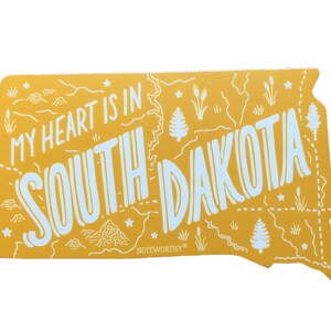 Pu&ograve; includere: Adesivo giallo con un contorno dello stato del Dakota del Sud. Il testo "My heart is in South Dakota" &egrave; scritto in lettere bianche. L'adesivo ha un logo "Noteworthy" nell'angolo in basso a sinistra.