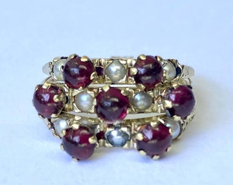 May include: A gold ring with three rows of red gemstones and white pearls. The ring is set with a total of 12 gemstones and 12 pearls.