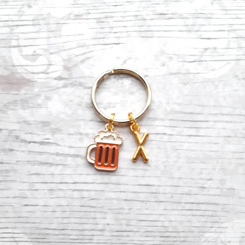 May include: Gold keychain with a beer mug charm and a letter X charm.