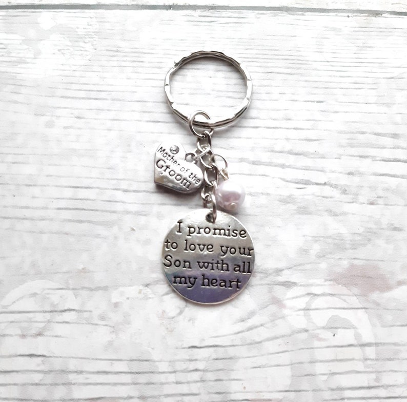 May include: Silver keychain with a heart charm that says "Mother of the Groom" and a round charm that says "I promise to love your Son with all my heart".