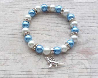 May include: A blue and white beaded bracelet with a silver dinosaur charm.