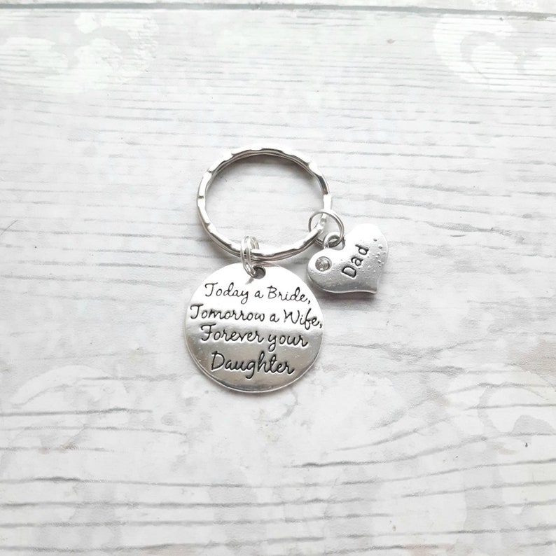 May include: Silver keychain with a round charm that reads "Today a Bride, Tomorrow a Wife, Forever your Daughter" and a small heart charm that reads "Dad".