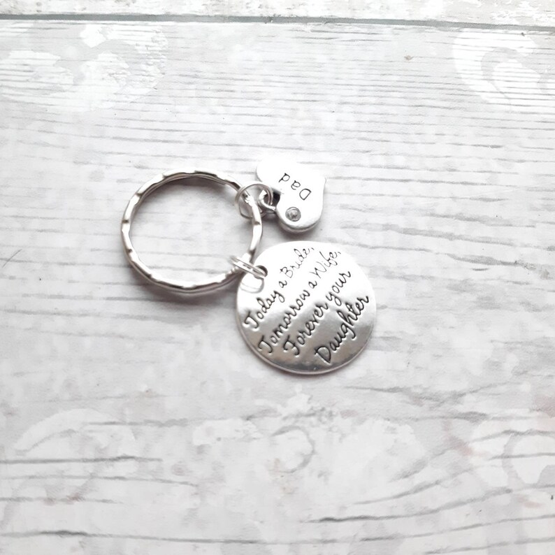 May include: Silver keychain with a round charm that reads "Today a Bride, Tomorrow a Wife, Forever your Daughter" and a small heart charm that reads "Dad".