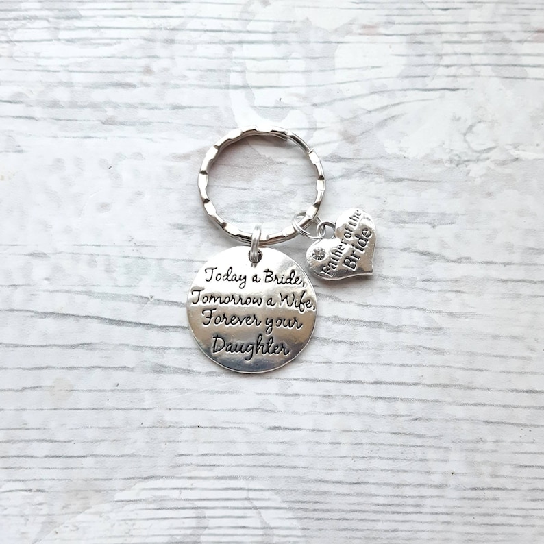 May include: Silver keychain with a round charm that reads "Today a Bride, Tomorrow a Wife, Forever your Daughter". A smaller heart charm with the text "Father of the Bride" is attached to the keychain.