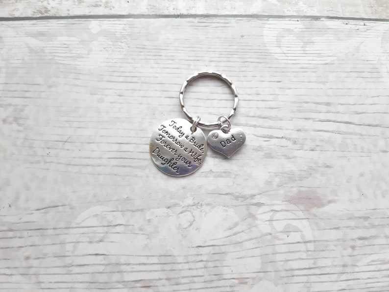May include: Silver keychain with a round charm that reads "Today a Bride, Tomorrow a Wife, Forever your Daughter" and a heart charm that reads "Dad".