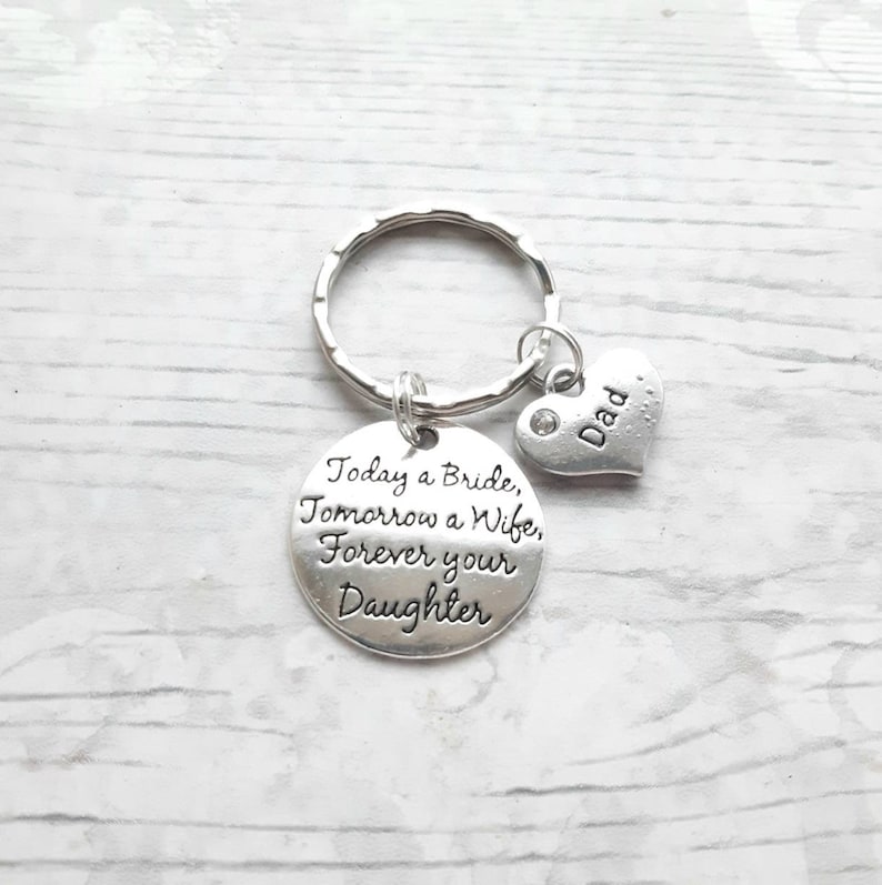 May include: Silver keychain with a round charm that reads "Today a Bride, Tomorrow a Wife, Forever your Daughter" and a small heart charm that reads "Dad".