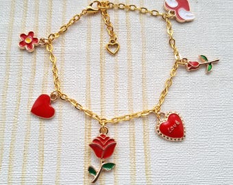 Puede incluir: Pulsera de cadena dorada con dijes de esmalte rojo y blanco, incluyendo corazones, flores y rosas. Los dijes tienen detalles dorados y el dije en forma de corazón dice "Love".