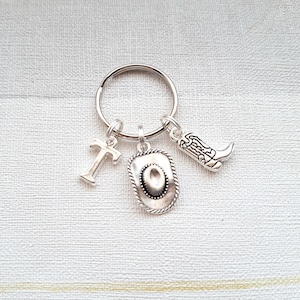 May include: Silver keyring with a cowboy hat, boot, and the letter T charm.